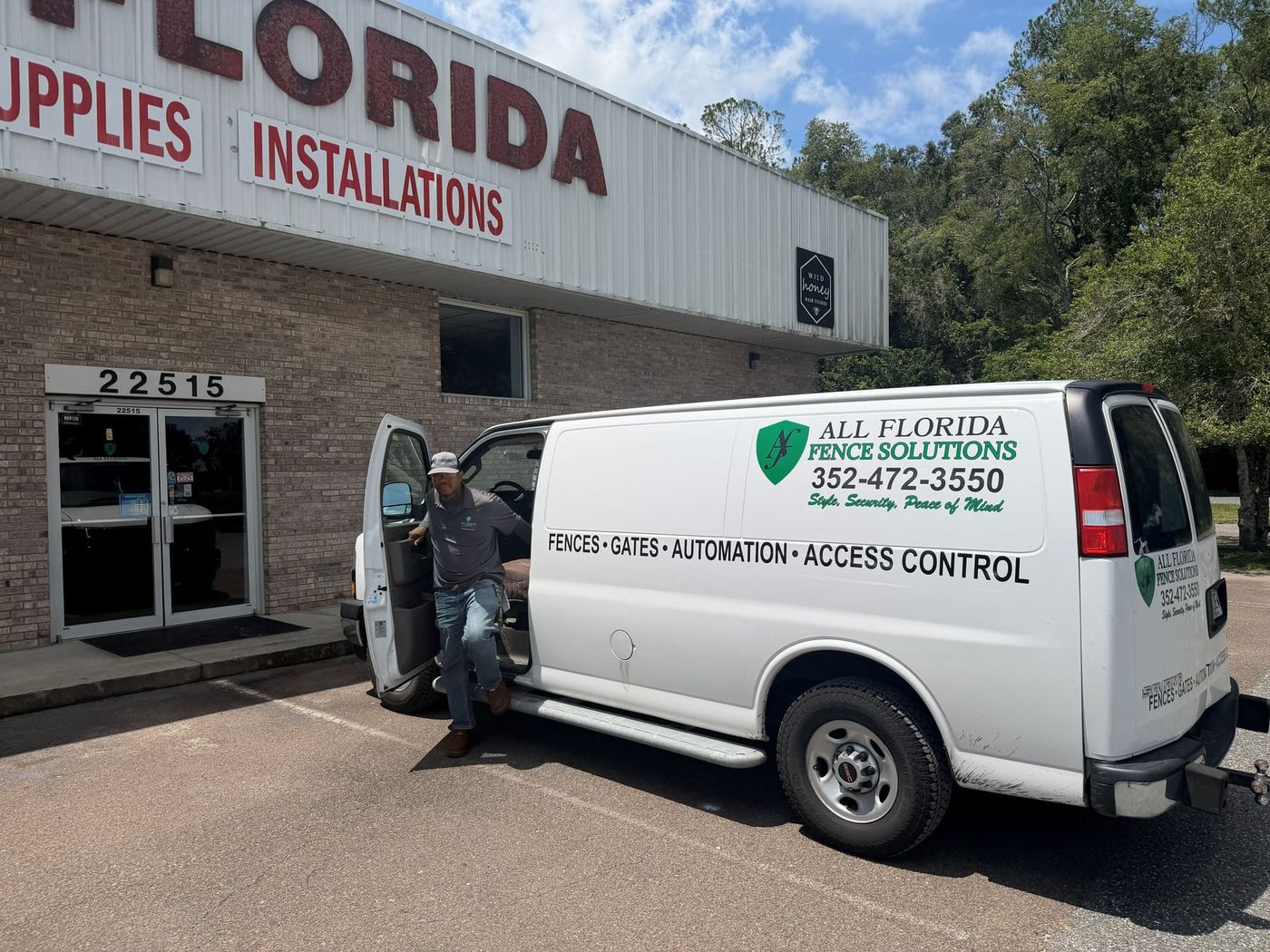 All Florida gate automation technician stepping out of the company's branded automation service van, parked in front of the All Florida Fence Solutions building.