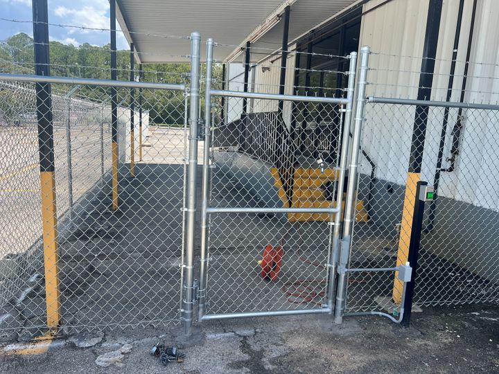 Keypad access control device mounted at a chain-link pedestrian gate.