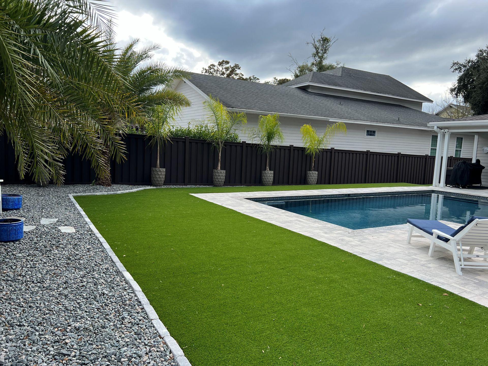 Black privacy fence enclosing a backyard pool and artificial turf lawn.