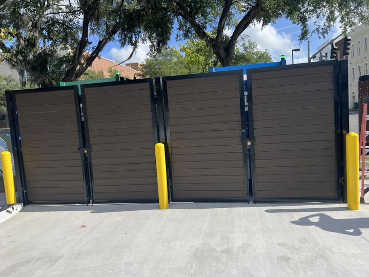 Tall security-panel gates protected by yellow bollards.