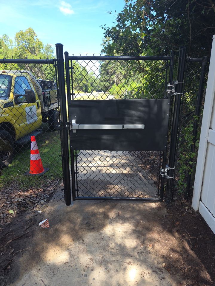 Black commercial gate with keypad access hardware and an All Florida service truck.