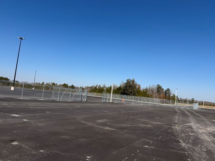 Wide industrial perimeter chain-link fence and gate along a paved lot.