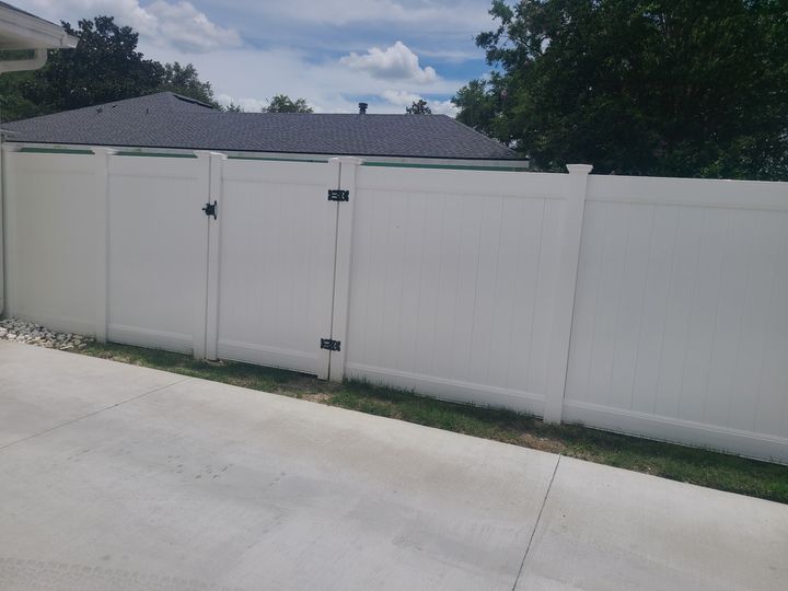 White vinyl privacy fence with a matching gate beside a residential driveway.
