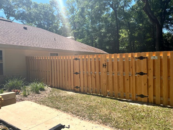 Wood shadowbox privacy fence and gate with decorative black hardware.