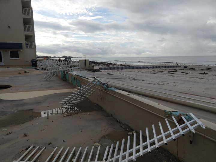 Extensive storm damage to a vinyl picket guardrail and perimeter barrier along a multi-story building.