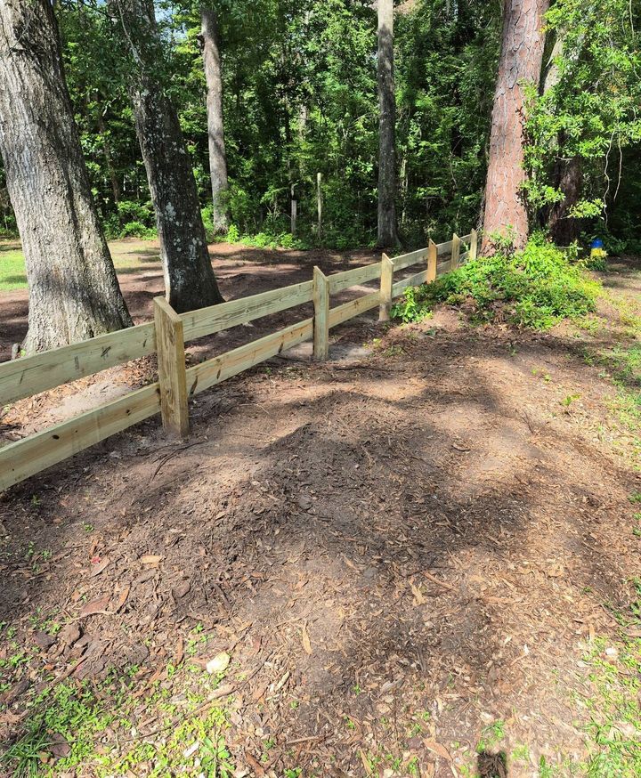 Three-rail wood fence installed around mature trees.