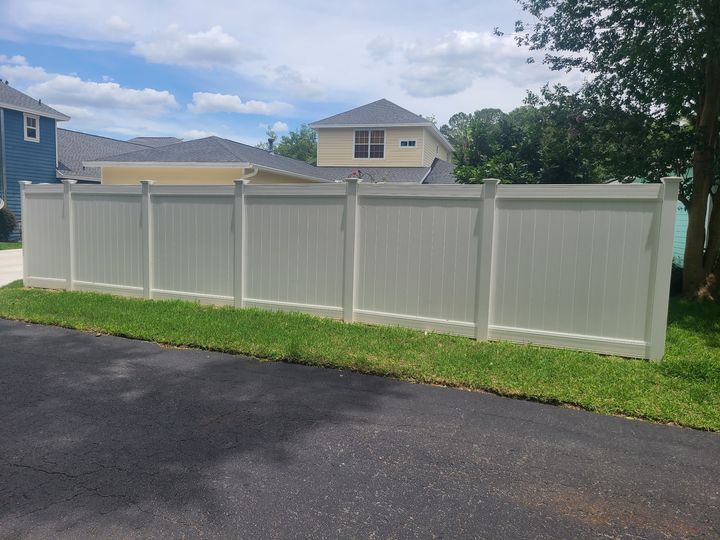 White vinyl privacy fence along a residential driveway.