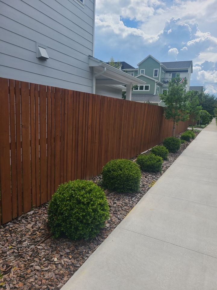 Stained wood privacy fence bordering a landscaped residential walkway.